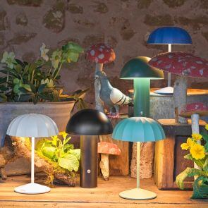 An eclectic mix of mushroom outdoor table lamps bundled onto a table decorated with toadstools and a cast iron pigeon.