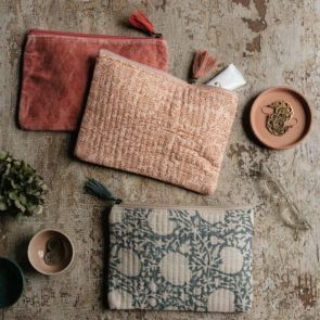 Three block printed pouches in cotton and velvet laid on a table surrounded by trinkets.