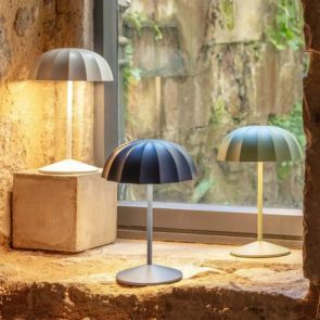 Three umbrella table lamps in grey, navy and green illuminating the rustic window ledge.